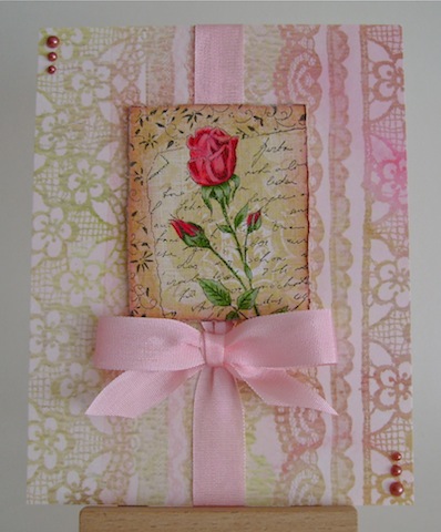 red rose on pink and beige lace paper with pink ribbon and pearls