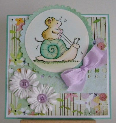 mouse riding aqua coloured shell with white flowers and purple bow