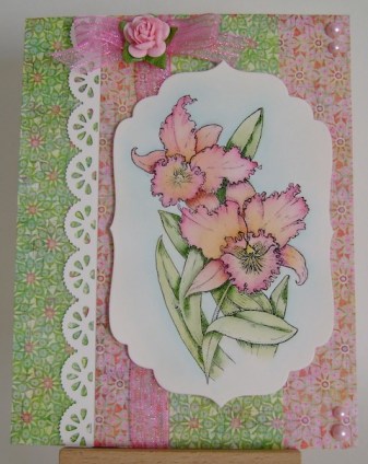 pink and yellow orchid on pink and green designer floral paper with pink bow and pink pearls