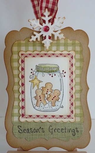 tag in red, green and brown with jar of gingerbread cookies, a season's greetings sentiment with a red check bow at the top with a white snowflake sponged brown on the edges and red gem in the middle