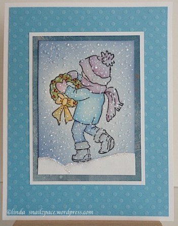 christmas card with boy walking through snow and carrying a wreath