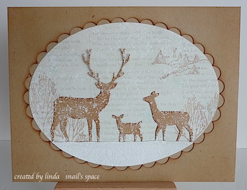 christmas card with deer in snow around trees with a scallop frame surrounding the image