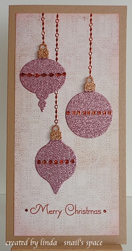 christmas card in pink with three glittery ornaments and merry christmas sentiment