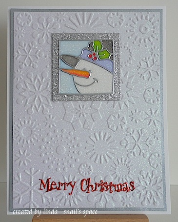copyright linda @ snail's space and described here for people with disabilities; christmas card with snowman portrait and a red merry christmas sentiment on a white snowflake embossed card base