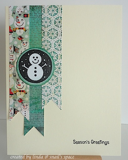 christmas card in teal with snowman and season's greetings sentiment with three printed paper banners