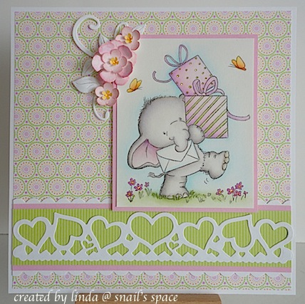 copyright linda @ snail's space and described here for people with disabilities; birthday card in pinks and greens featuring a stamped and coloured cute elephant carrying some presents plus a die cut white heart border at the bottom